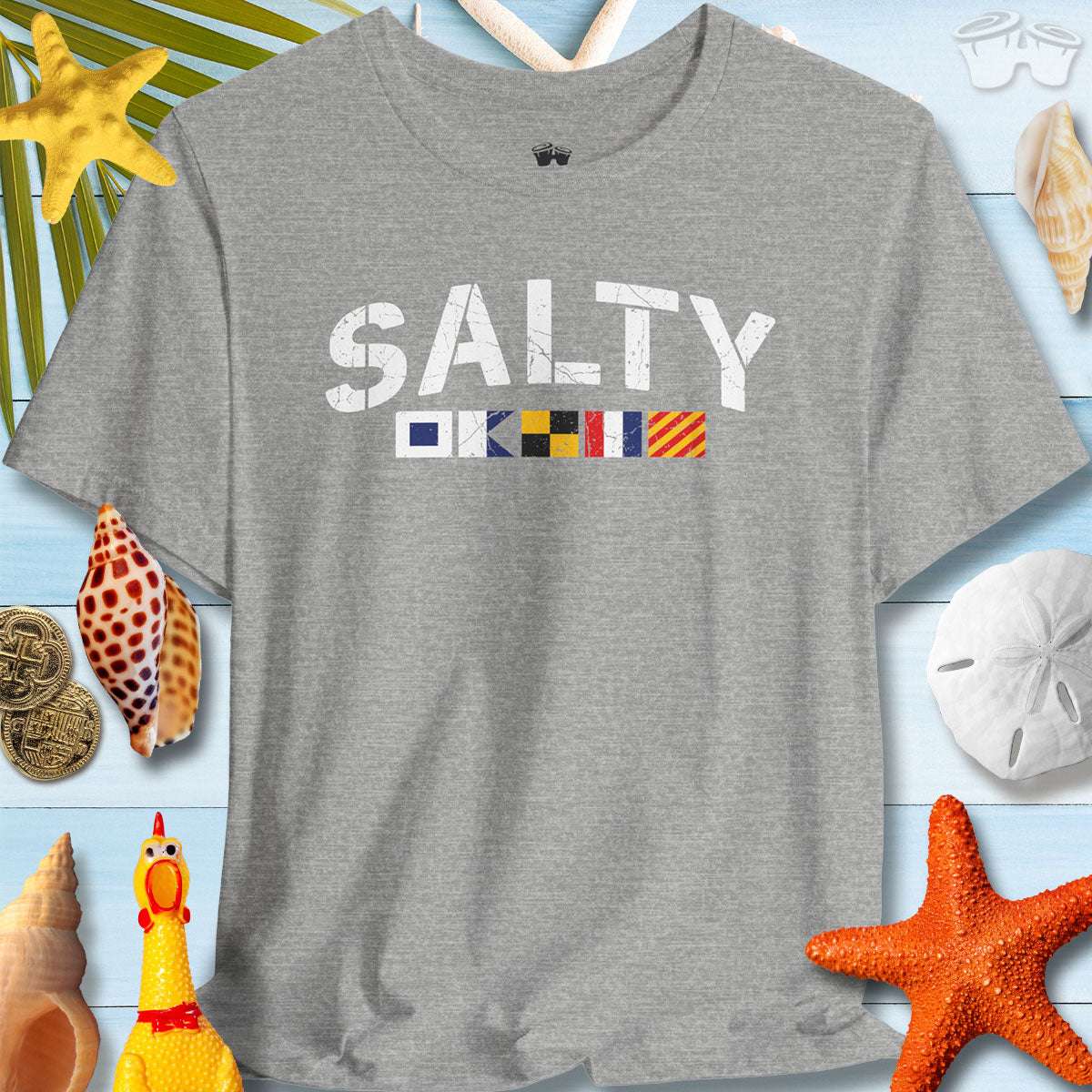 Salty Nautical Signal Flags T-Shirt on a beach-themed background with seashells and starfish.