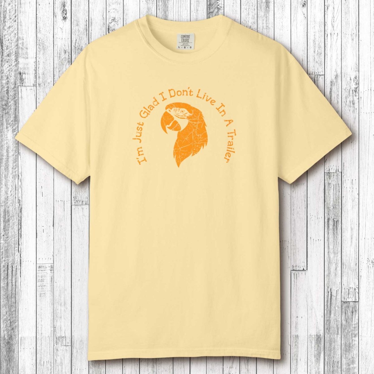 Beige t-shirt with orange graphic and text on a wooden surface
