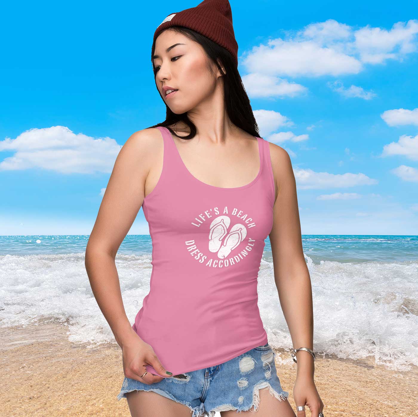 Woman wearing a pink tank top with a beach-themed design on a beach background