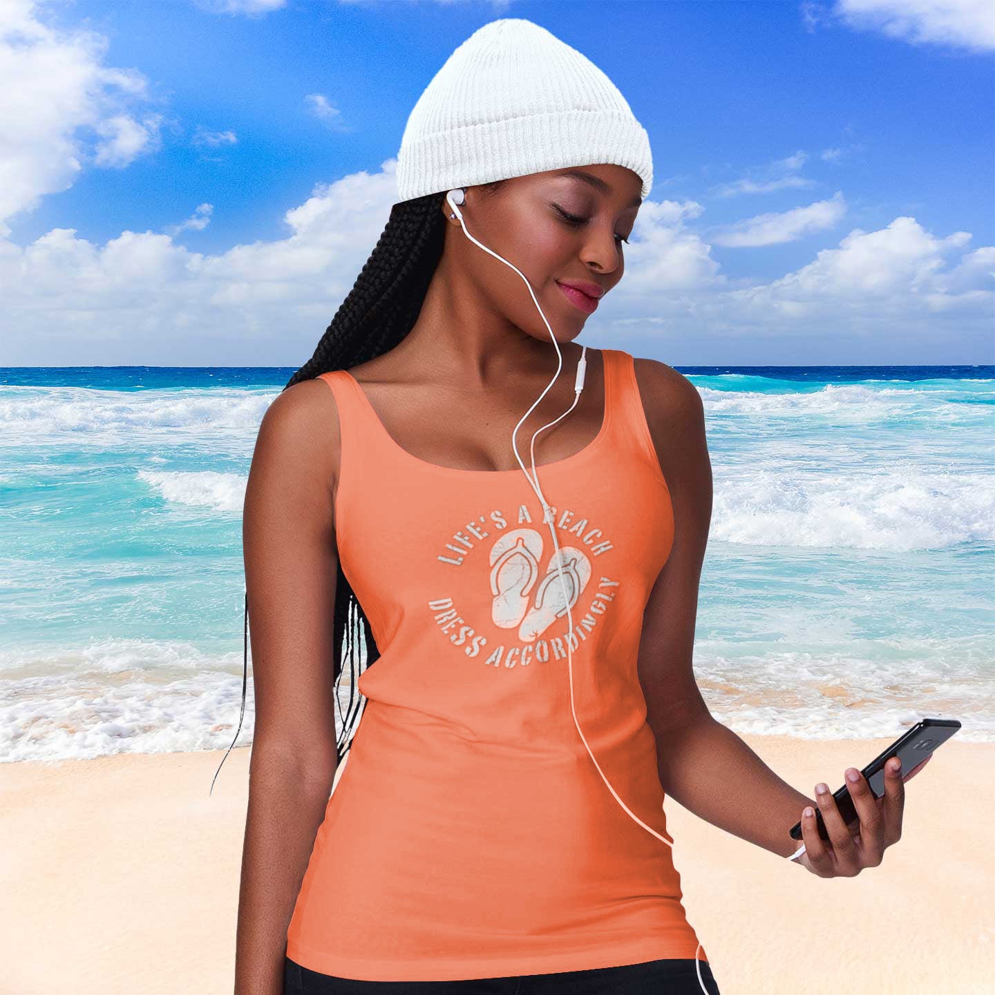 Woman on a beach wearing an orange tank top with a quote, listening to music.