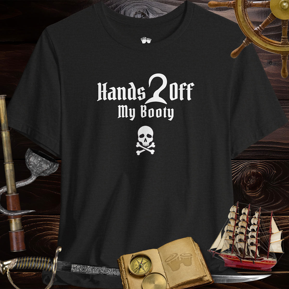 A Heather Black T-Shirt standing on it's own in front of a dark wood ships hull. Surrounded by a Helm, a spyglass with a hook, a ship's log, a sword, and model ship.
