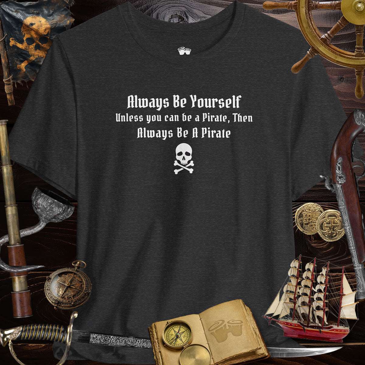 Always Be Yourself | Funny Pirate T-Shirt on a dark background surrounded by pirate-themed props.