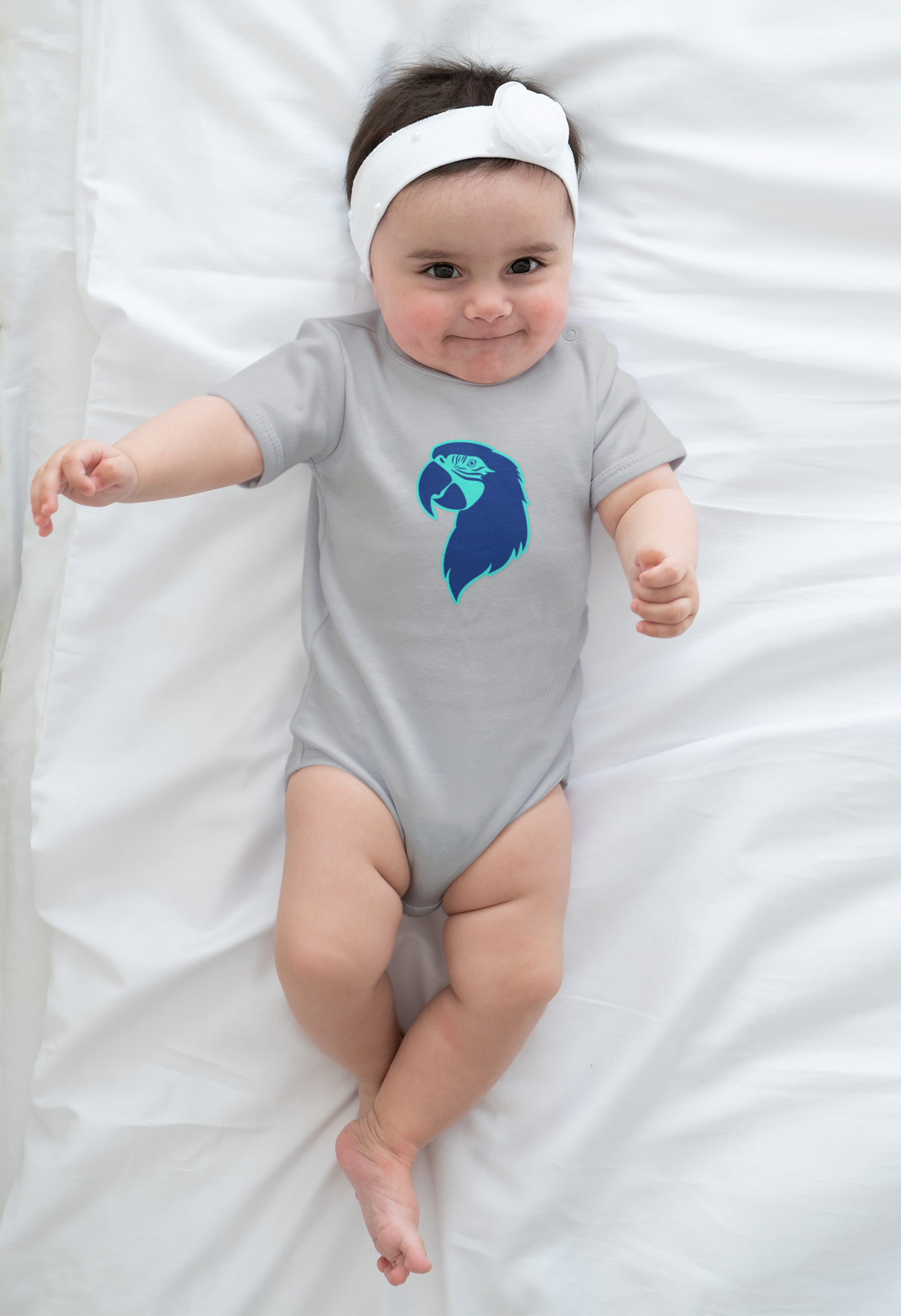 Baby wearing a gray onesie with a blue Parrot Head design on a white blanket