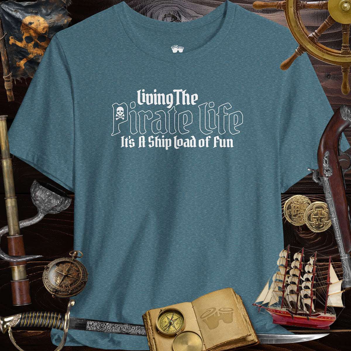 Pirate's Life unisex tee in teal, featuring playful design and surrounded by pirate-themed accessories.