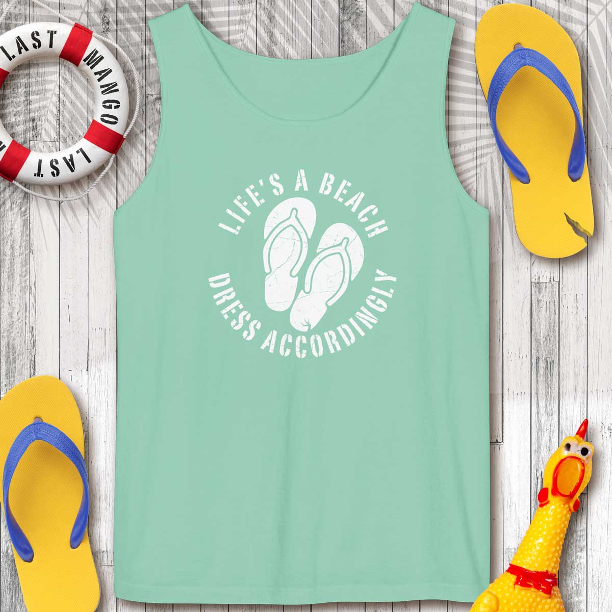 Island Reef green tank top with beach-themed design on a wooden surface with flip-flops and a life buoy.
