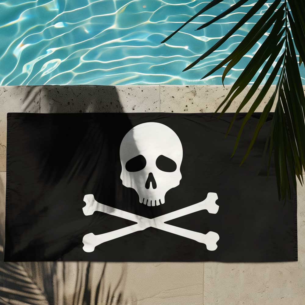 Black Beach Towel with Jolly Roger Pirate in white laying out by the pool