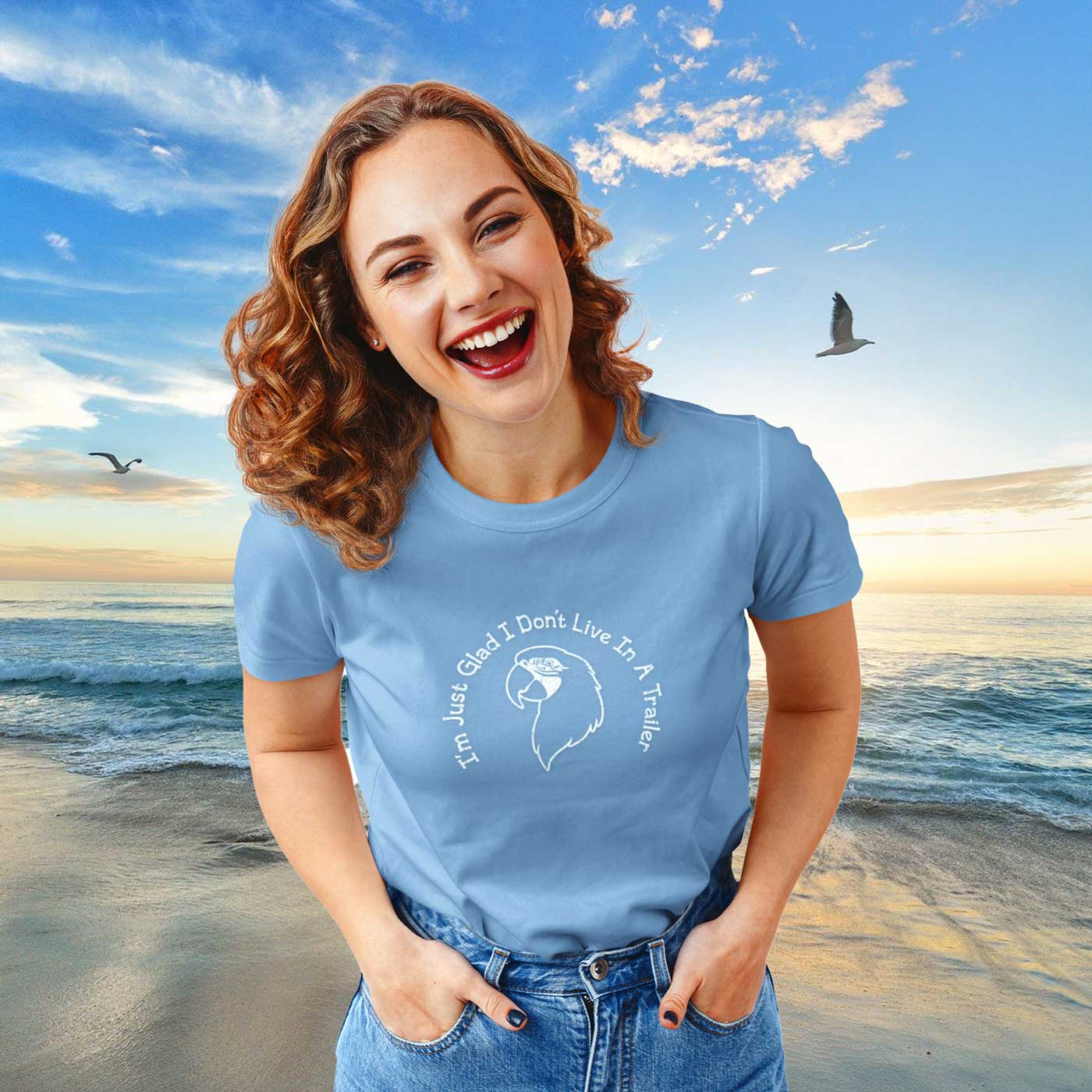 Woman wearing a blue t-shirt with a graphic and text on a beach with a sunset background