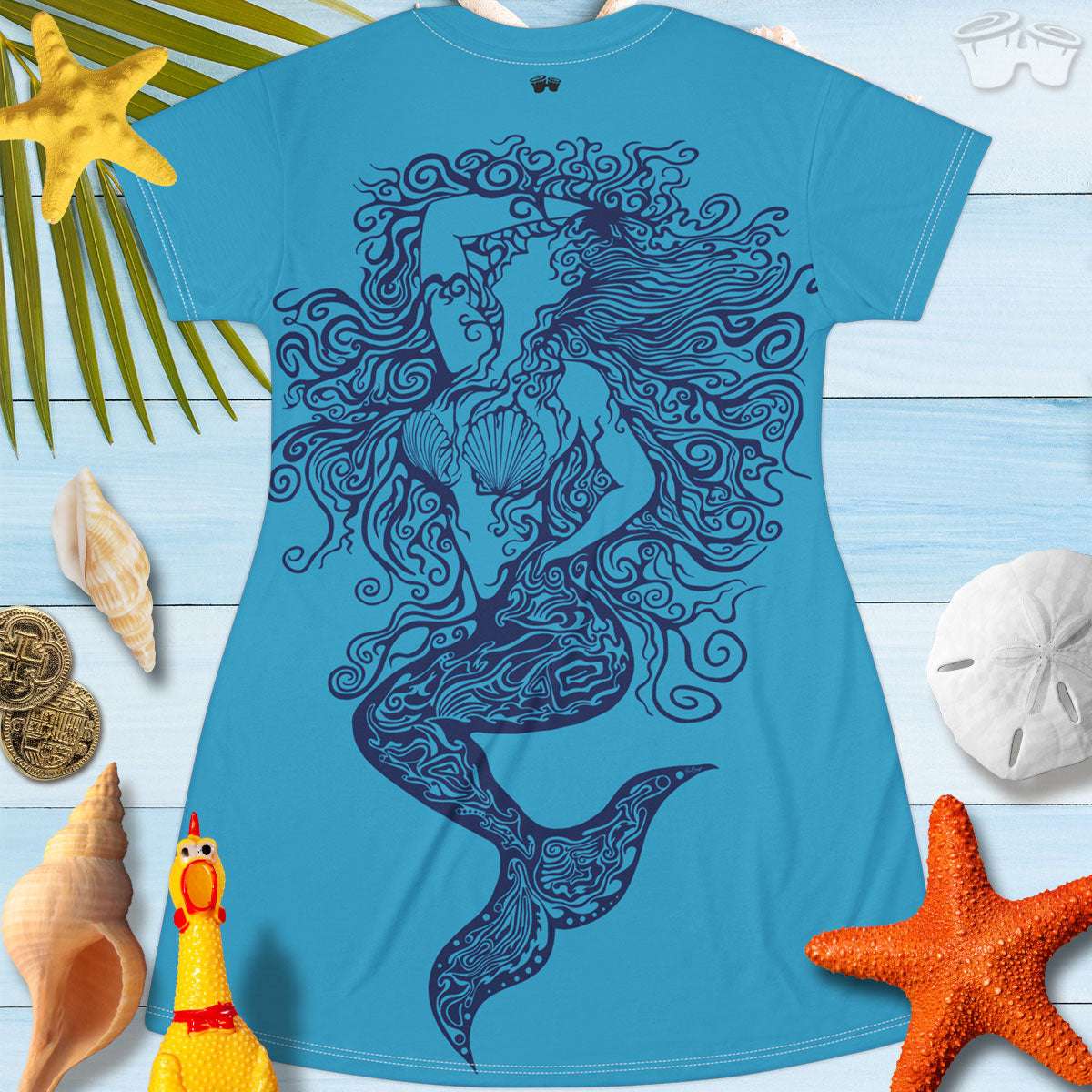 Back of a Bongo Beachwear T-Shirt Dress featuring a zentangle mermaid design hand drawn by RonBongo and printed on both sides of dress. laying on a wood floor surrounded by starfish, seashells and and sand dollars.