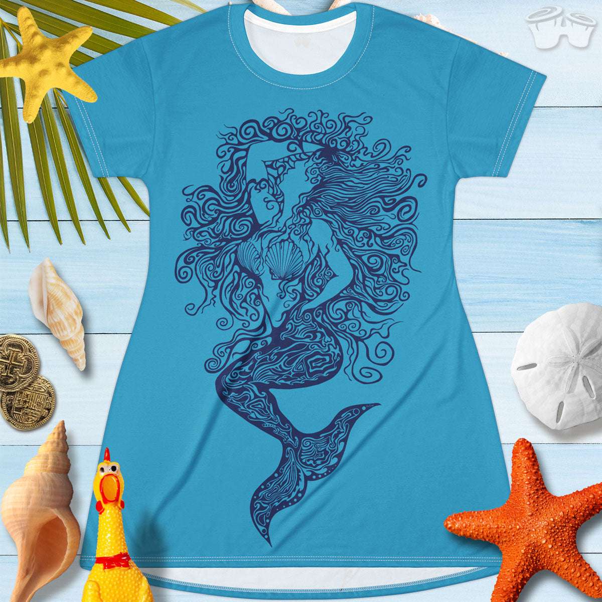 T-Shirt Dress featuring a zentangle mermaid design hand drawn by RonBongo and printed on both sides of the dress. laying on a rustic wood deck surrounded by seashells and and sand dollars and starfish