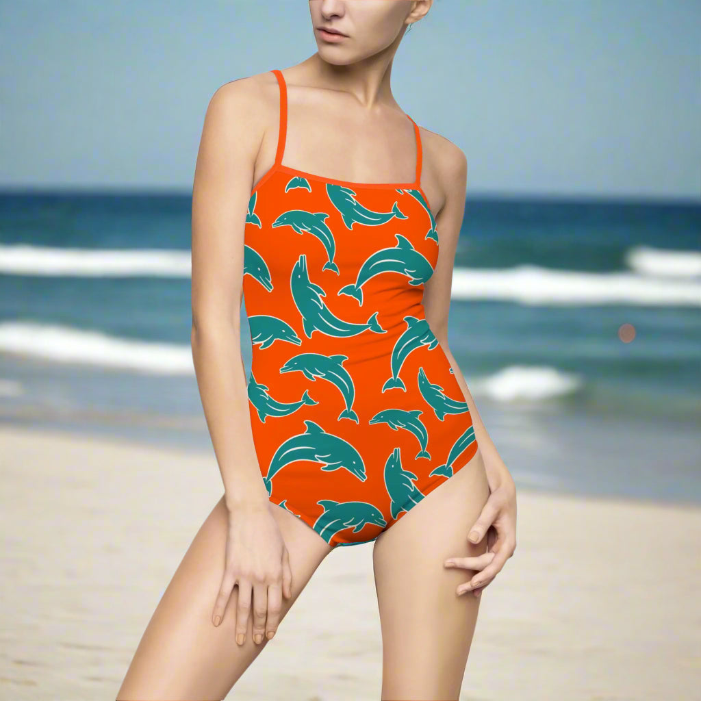 Model in Dolphins Orange One Piece with Teal and White Dolphin Pattern standing in the ocean on beach day