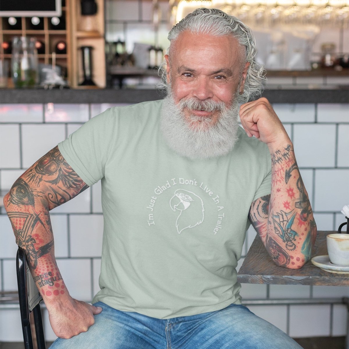 Man with tattoos wearing a light green t-shirt in a kitchen setting
