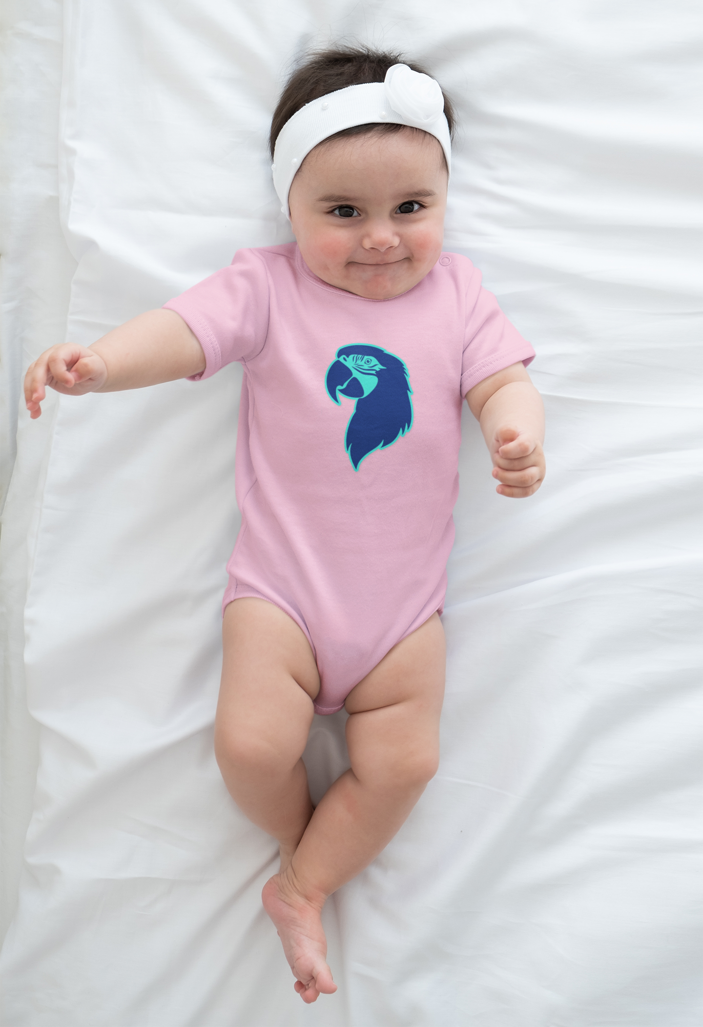 Baby wearing a pink onesie with a blue design on a white blanket