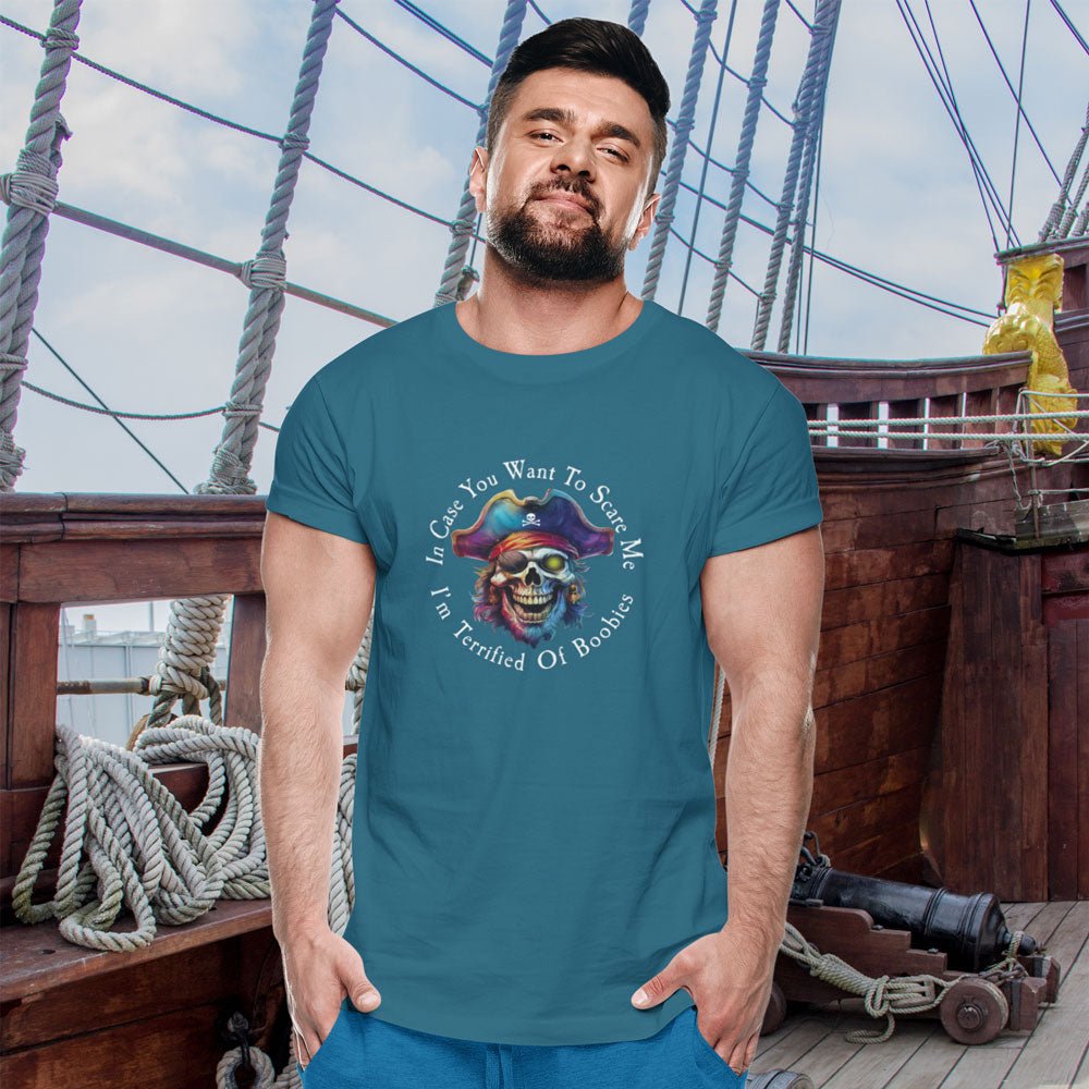 Man wearing a teal t-shirt with a pirate-themed graphic on a ship deck.