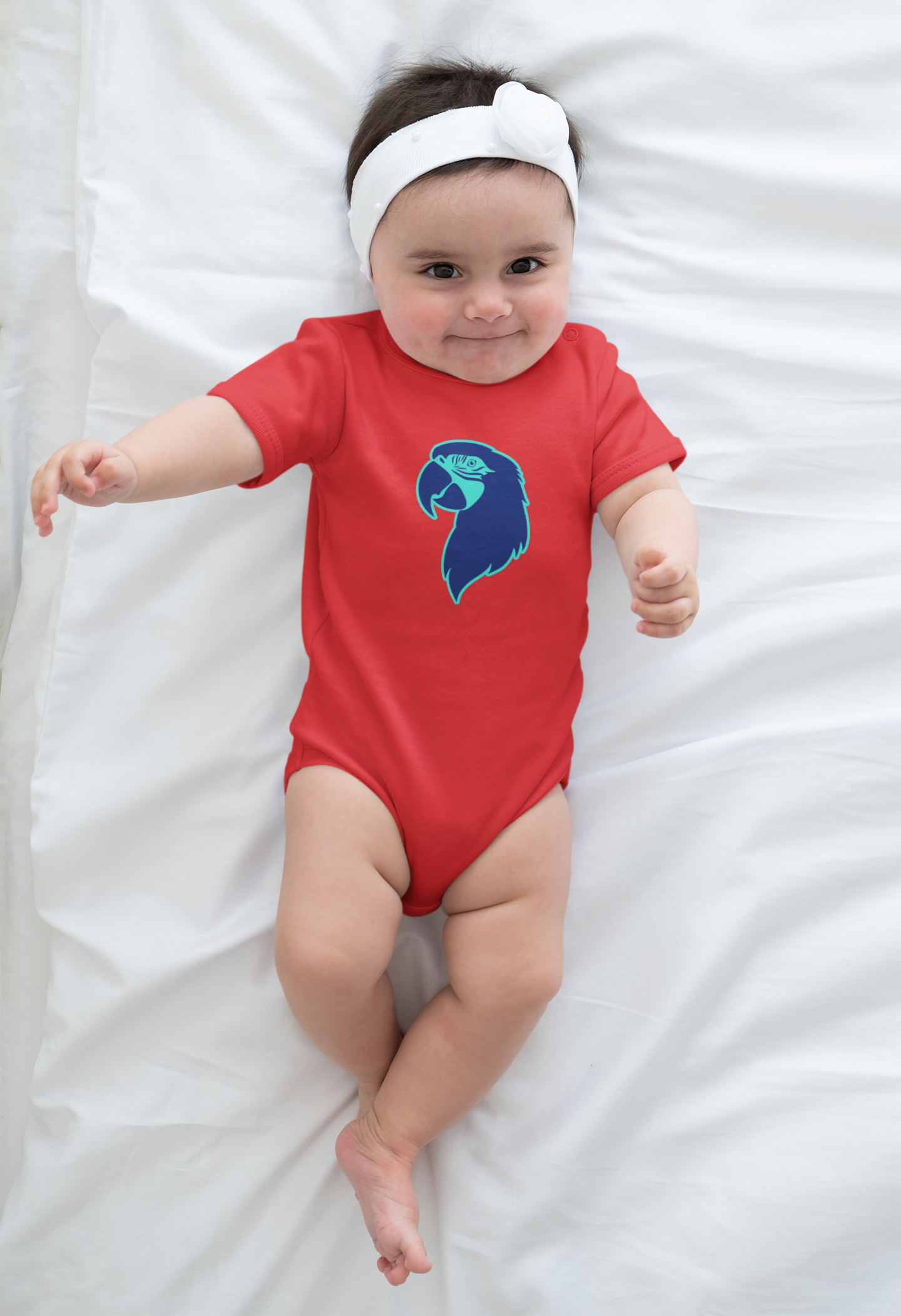 Baby wearing a red onesie with a blue parrot head logo on a white blanket