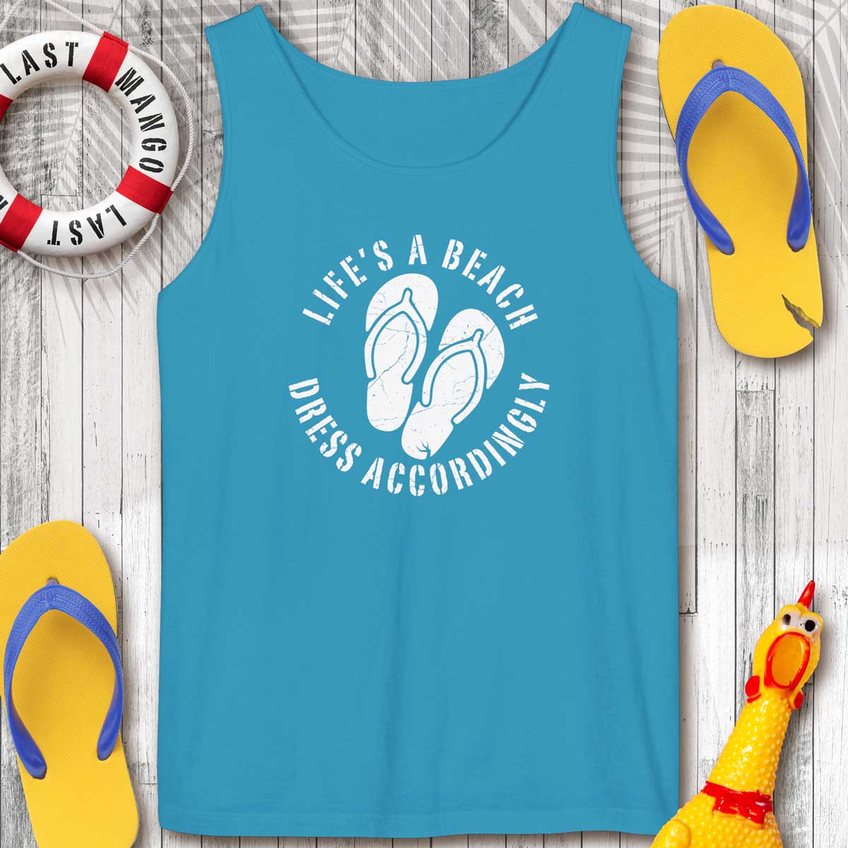 Sapphire Blue tank top with 'Life's a Beach Dress Accordingly' text and flip-flops on a wooden surface.