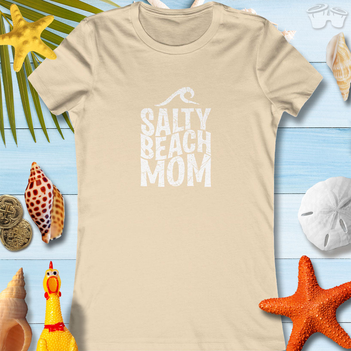 Women's beige Salty Beach Mom Tee, perfect for moms who love beach style, surrounded by seashells and coastal decor.