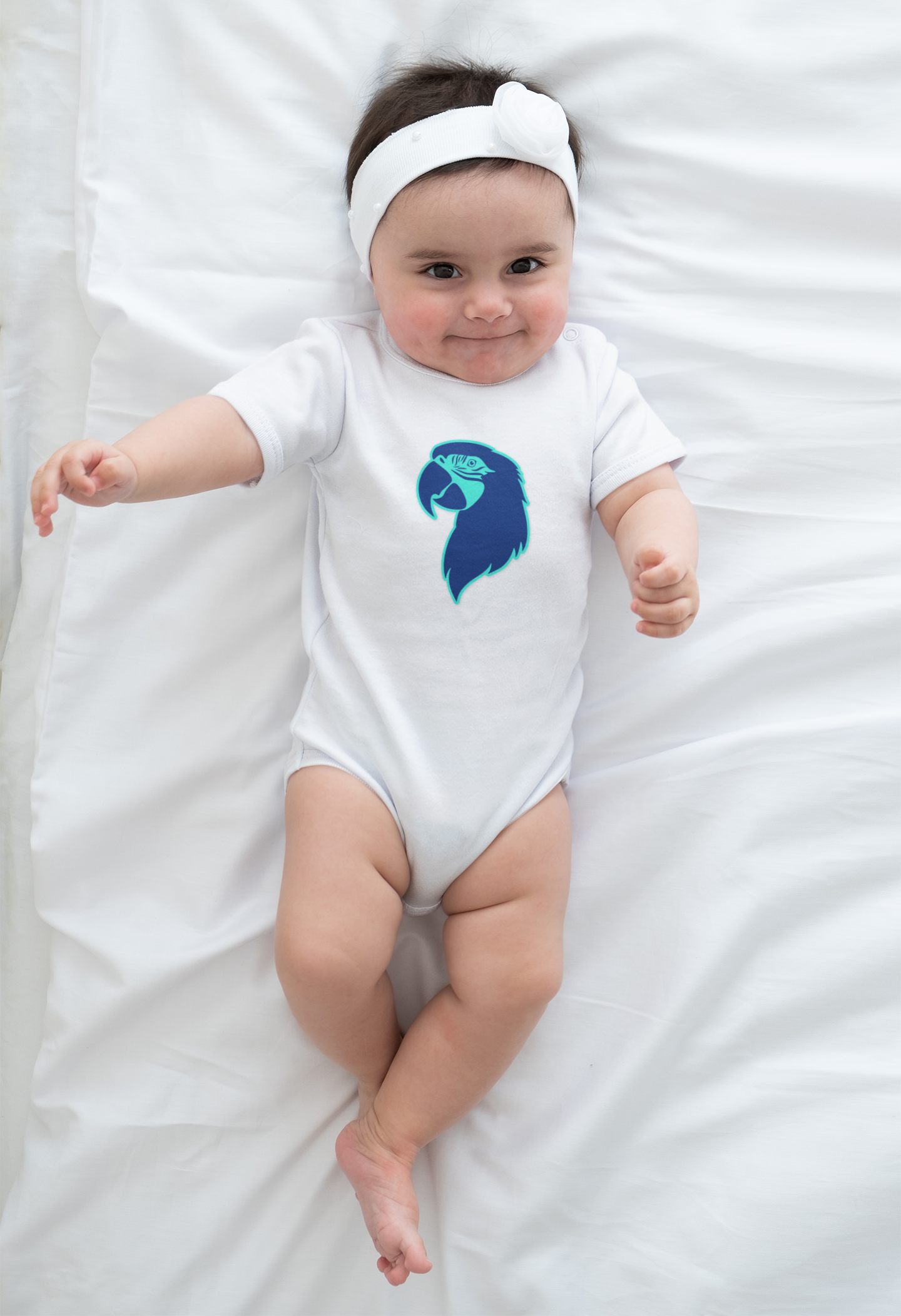 Baby wearing a white onesie with a blue parrot head design on a white background