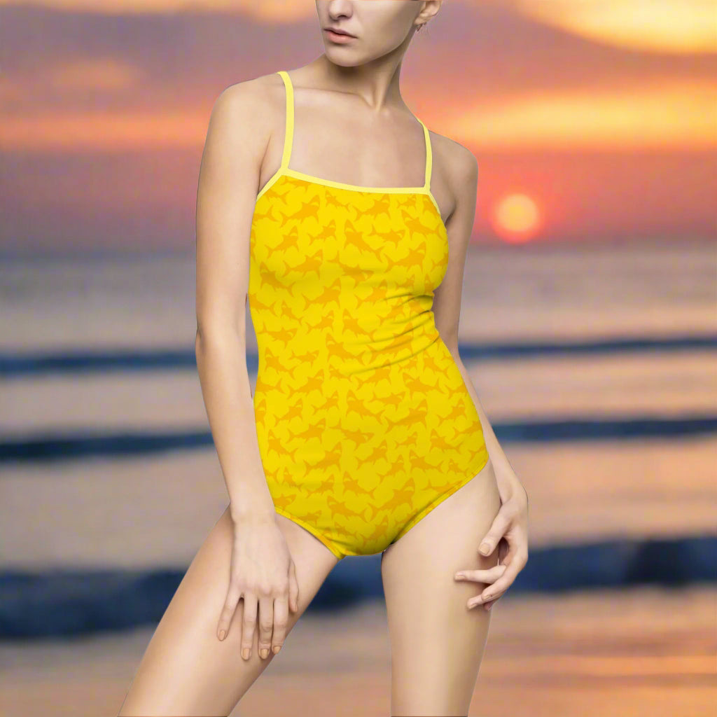 Model in bright yellow one piece bathing suit with shark pattern standing on the beach