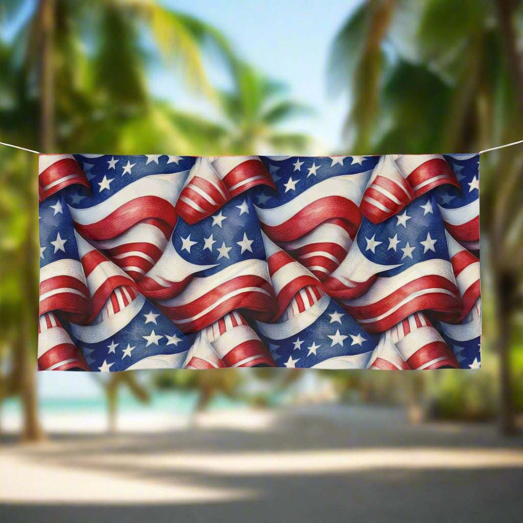 Americana beach towel sporting cool pattern of red, white and blue stars and stripes hanging on a line in a tropical paradise