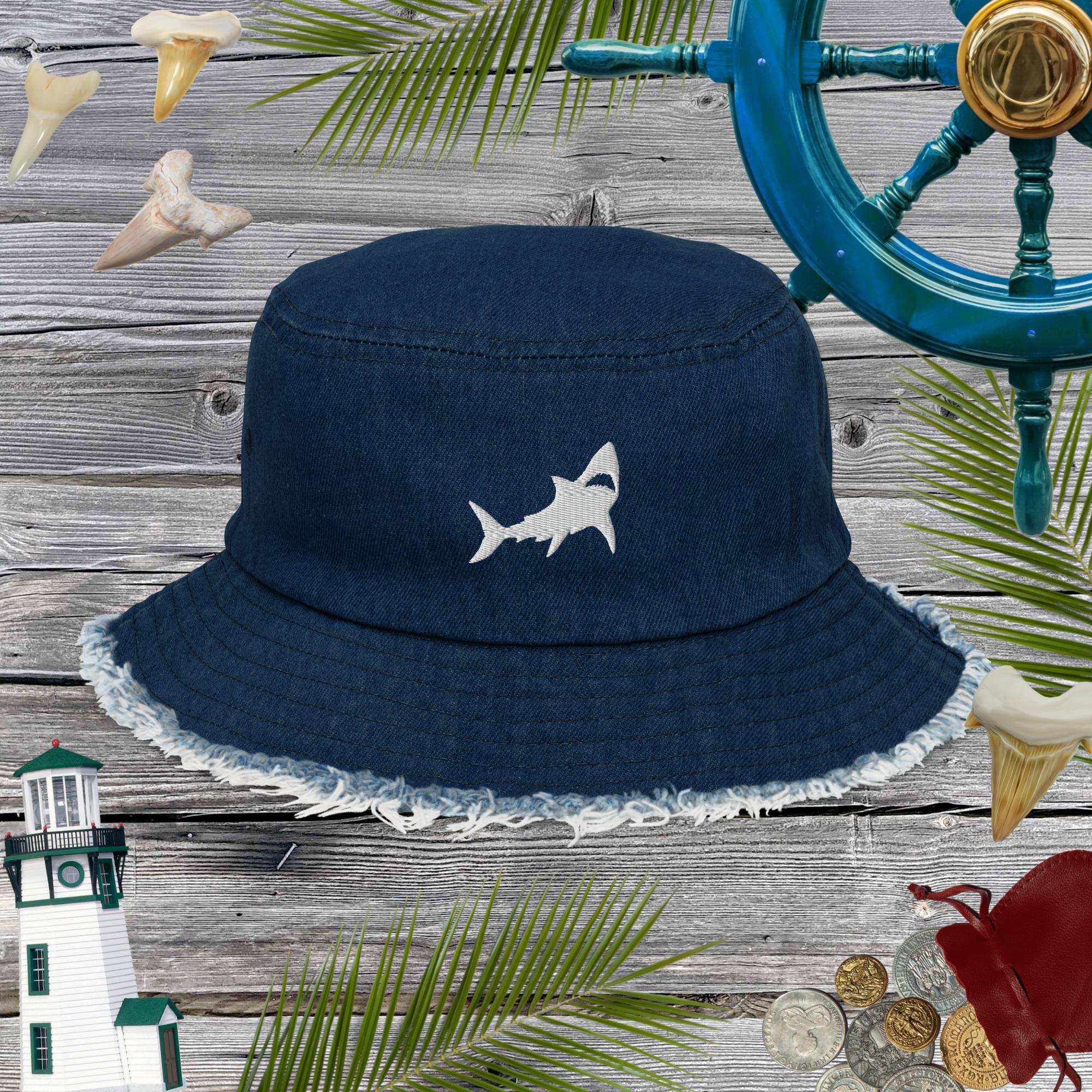 Navy blue bucket hat with shark design on a wooden surface with nautical decorations.