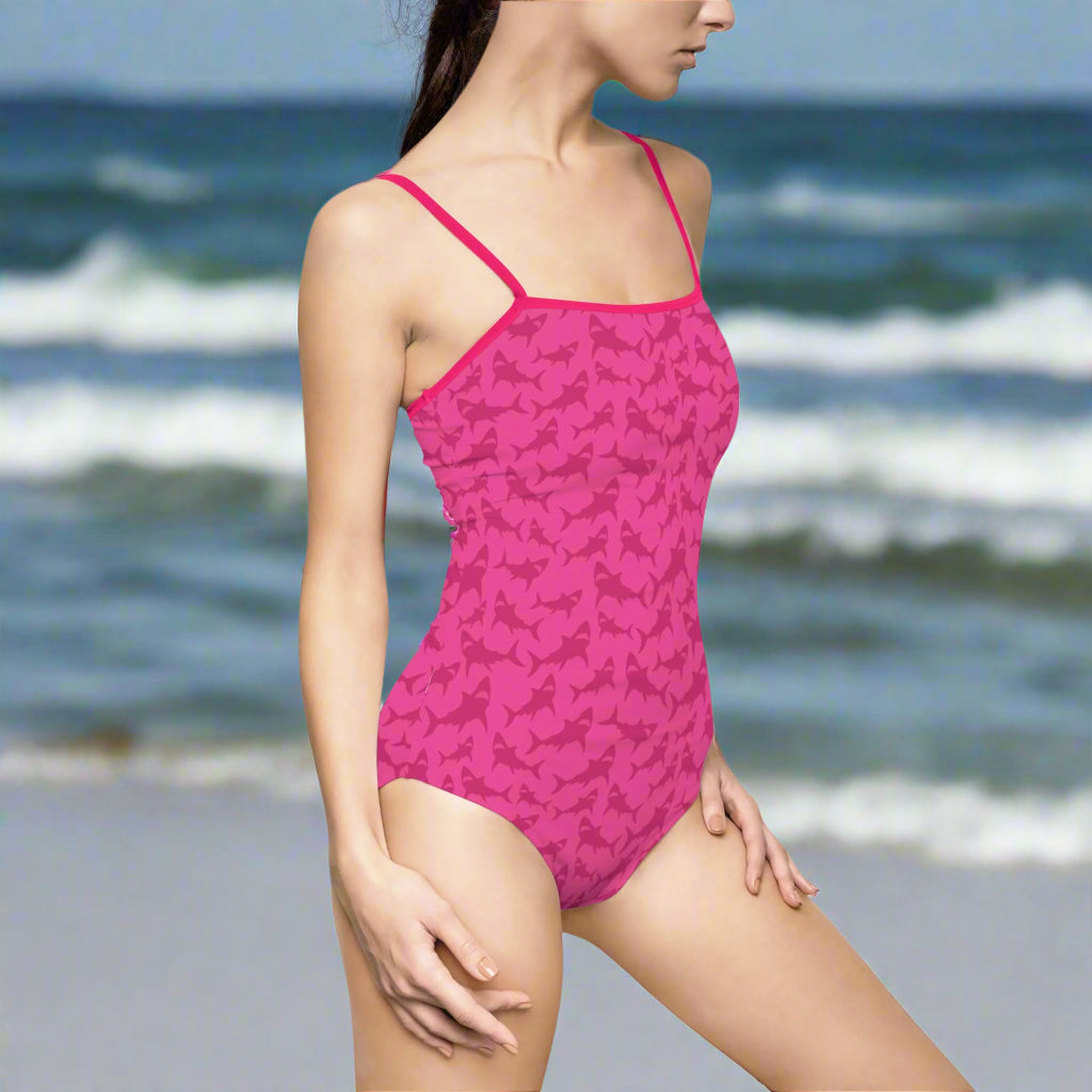 Woman in hot pink shark swimsuit standing near the ocean