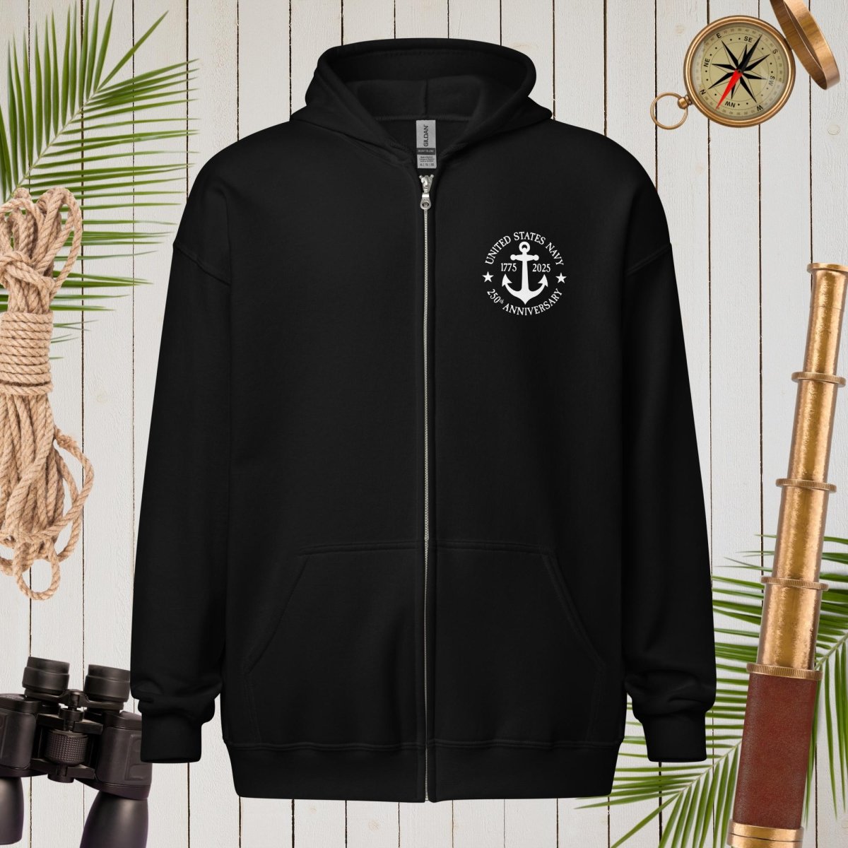 Black hoodie with a white emblem on a wooden background with nautical items.