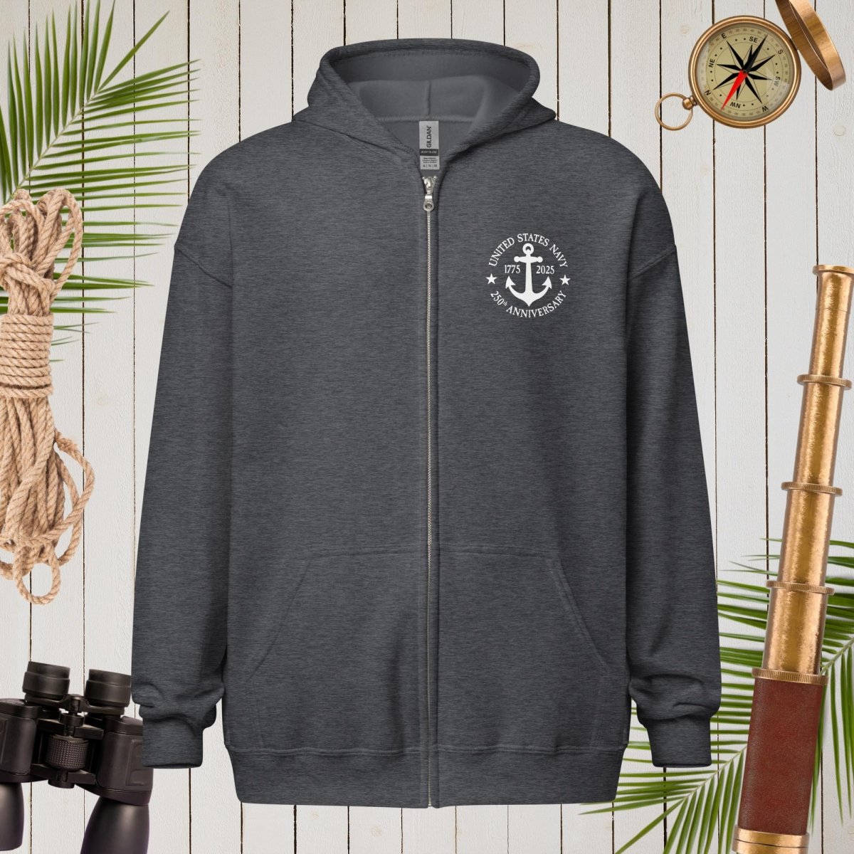Dark gray hoodie with a white emblem on a wooden background with nautical items.