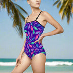 Woman standing in the sand in a cute one piece swimsuit with a Junonia seashell pattern