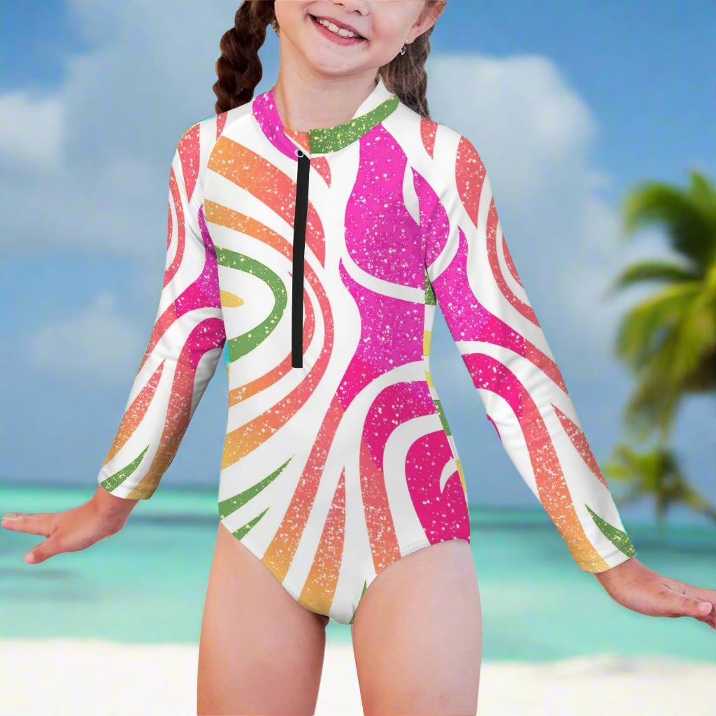 Child wearing a colorful long-sleeve swimsuit with a beachy background