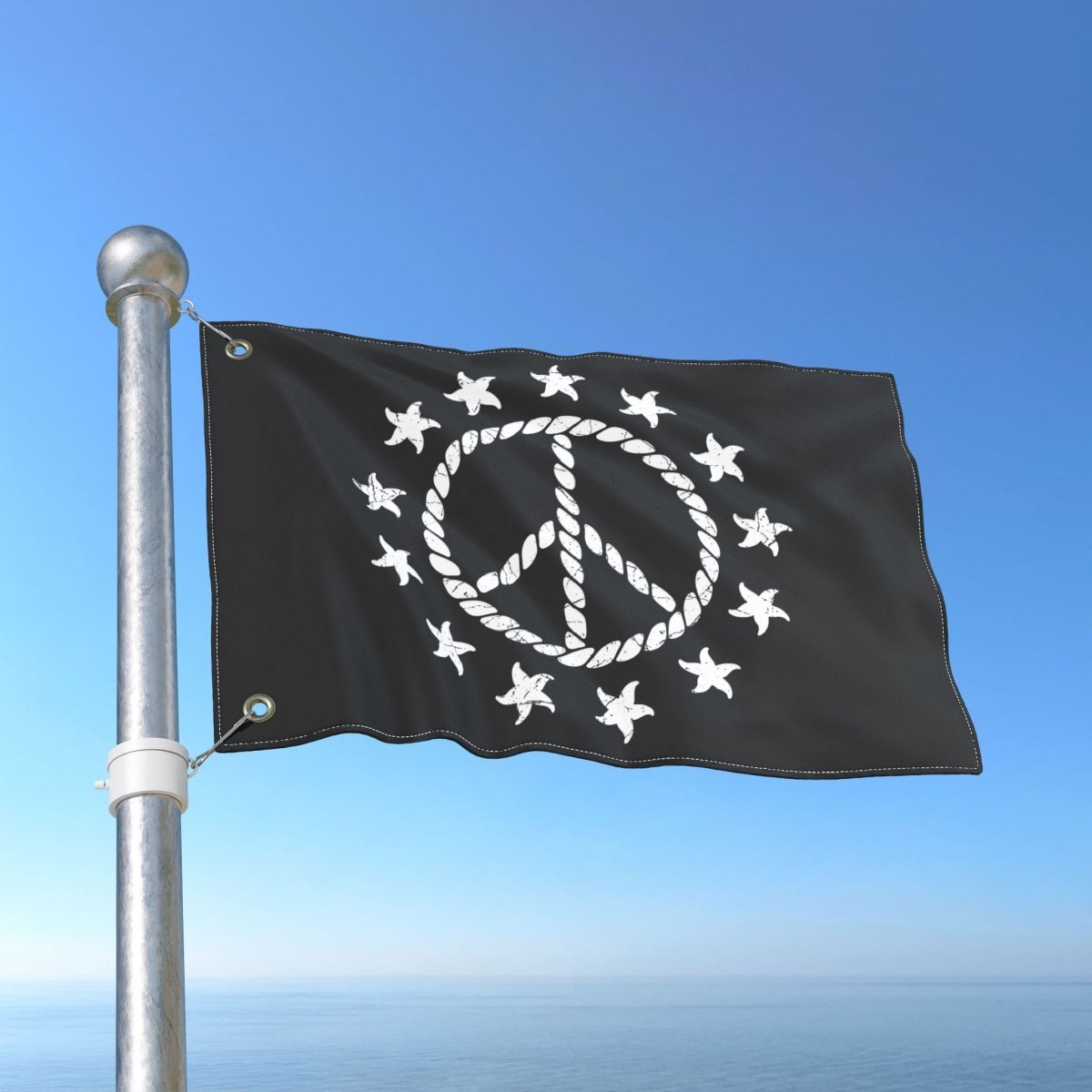 Black flag with white peace symbol and stars on a metal pole against a blue sky.