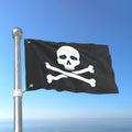 Pirate flag with skull and crossbones on a pole against a blue sky.