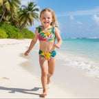 Cute little girl wearing a Colorful Kids Tropical Bikini set playing on a tropical island beach