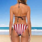 Woman wearing a red and white striped bikini on a beach with clear blue sky.