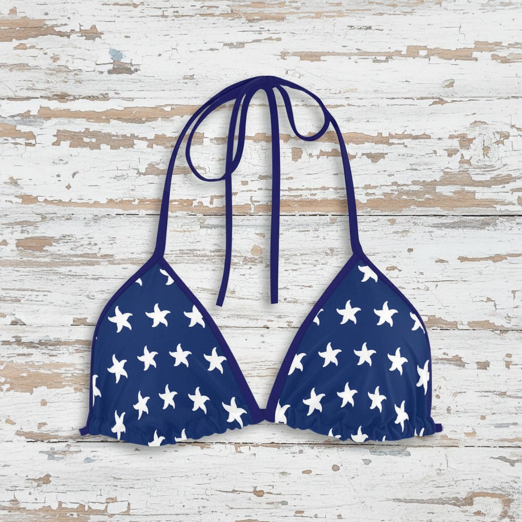 Navy blue bikini top with white star pattern on a faded wood background