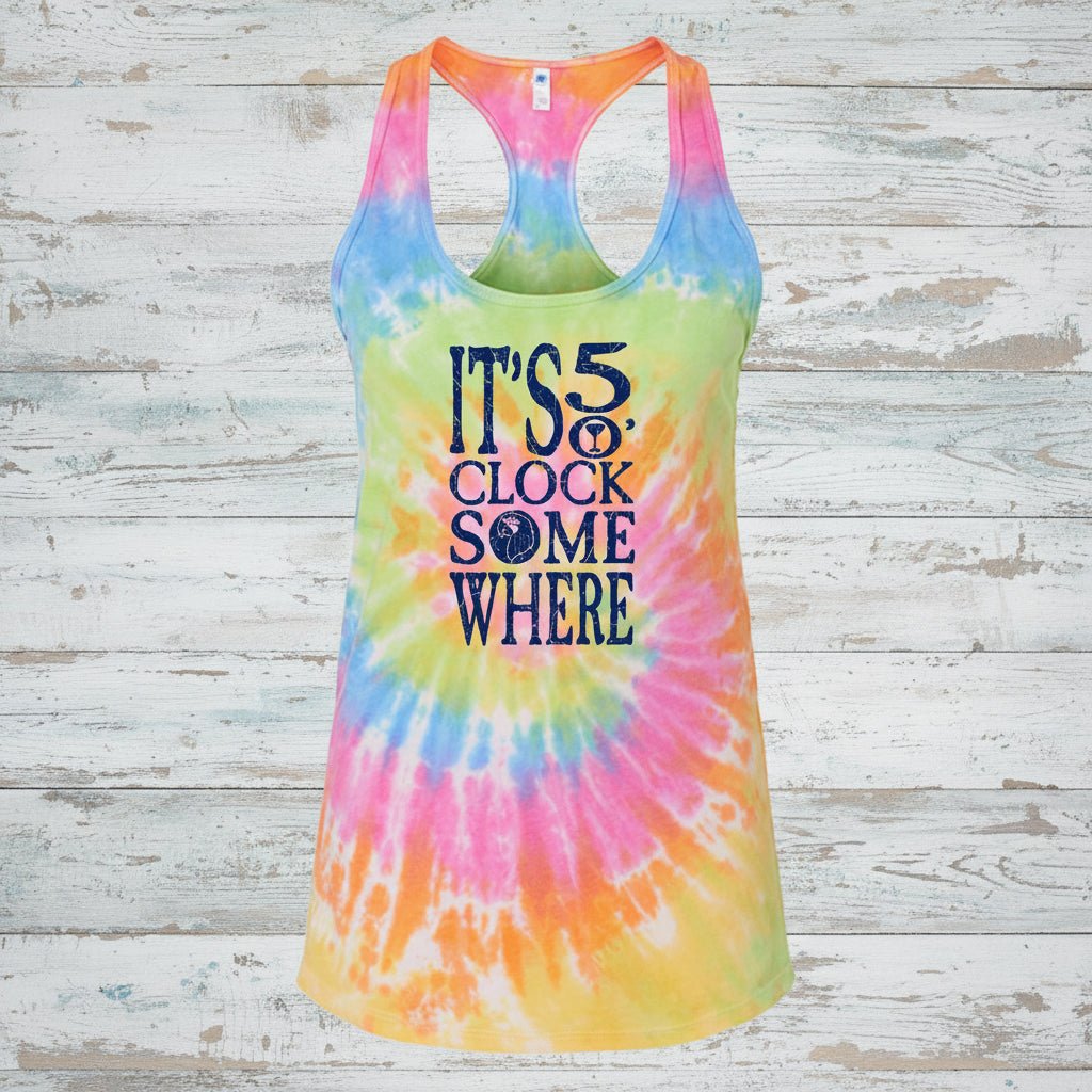 A women's racerback tank top with a vibrant rainbow tie-dye spiral pattern and the text 'IT'S 5:30 CLOCK SOMEWHERE' printed in navy blue on the front.