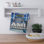 Towel with 'AMI Strong' text displayed on a shelf with a plant and bread basket.