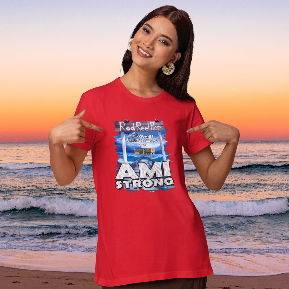 Woman wearing a red 'AMI Strong' t-shirt on a beach at sunset
