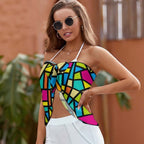 Woman wearing a colorful geometric-patterned top with white pants, standing outdoors.
