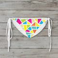 Colorful geometric patterned bikini bottom on a wooden surface