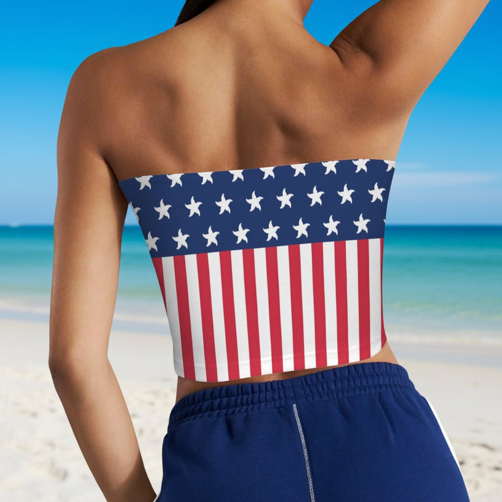 Swimwear model wearing a strapless top with American flag design and blue shorts looking out a the gulf from Pensacola Beach