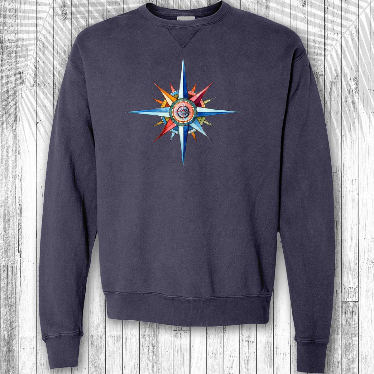 Navy blue sweatshirt with a colorful nautical compass design on a wooden background