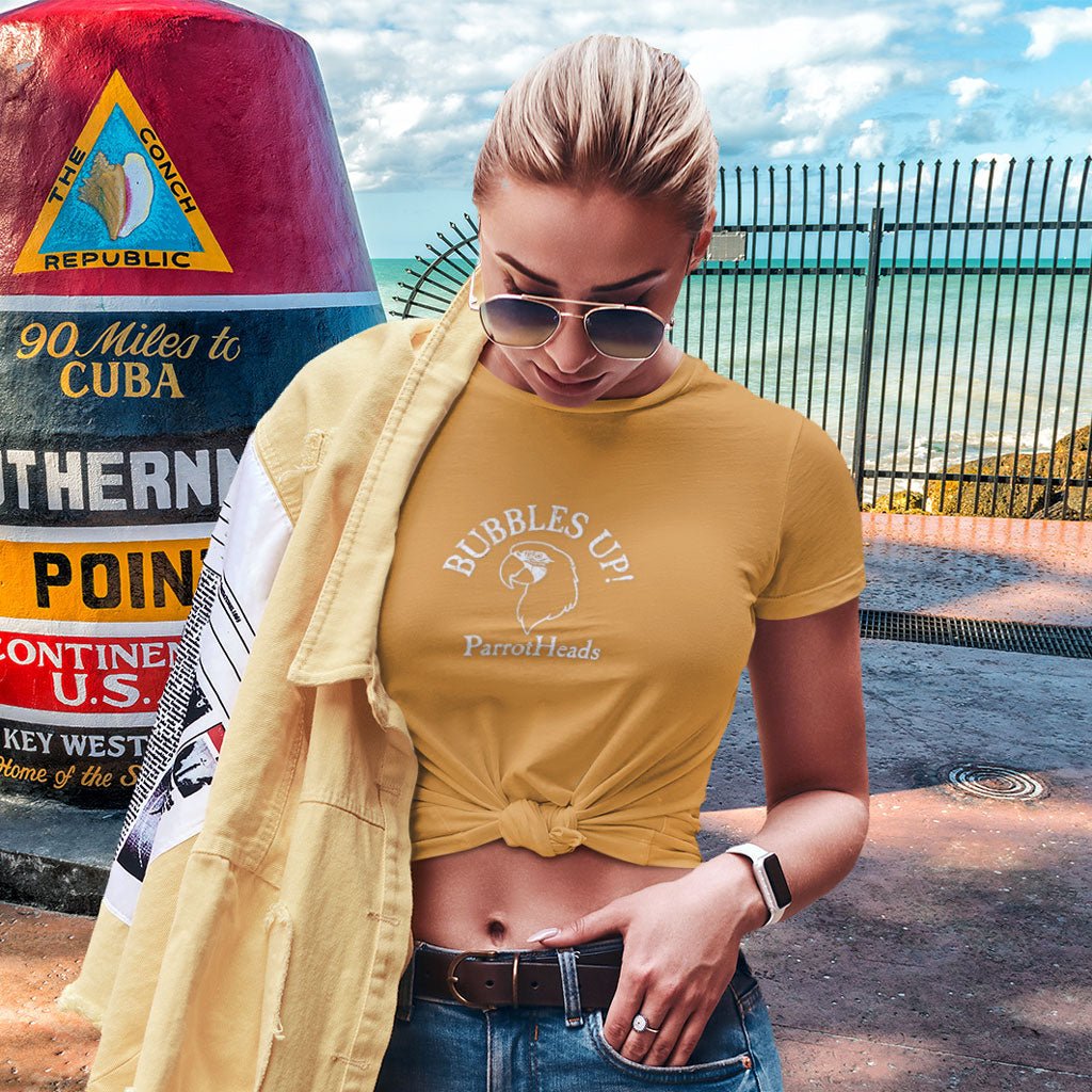 Woman wearing a yellow t-shirt with 'Bubbles Up!' text, standing next to The Southernmost Marker sign in Key West, Florida.