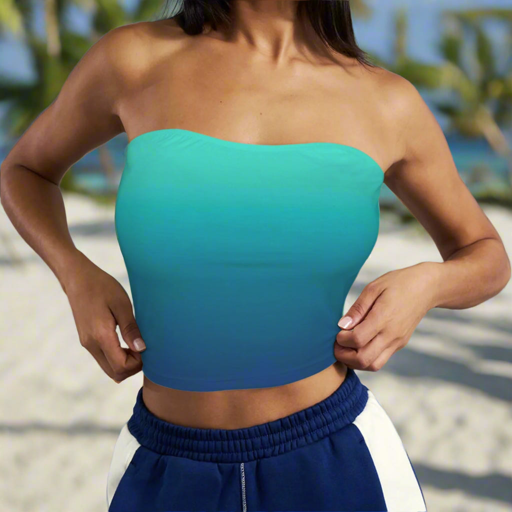Swimwear model wearing a teal to navy ombré strapless top and blue pants against a neutral background