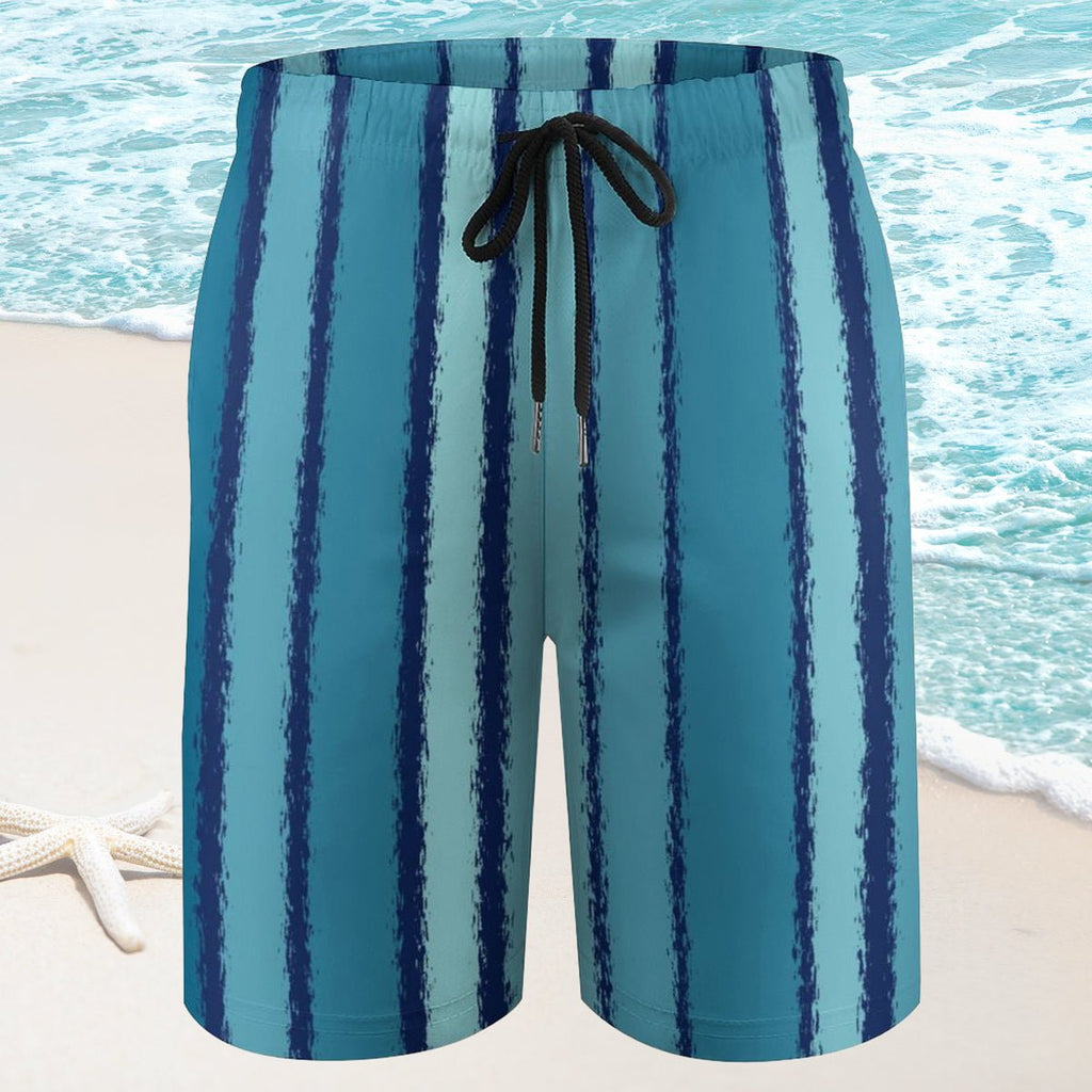 Blue and green striped swim shorts on a beach with ocean in the background