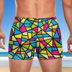 Backside of Colorful geometric patterned swim shorts for men with a beach background