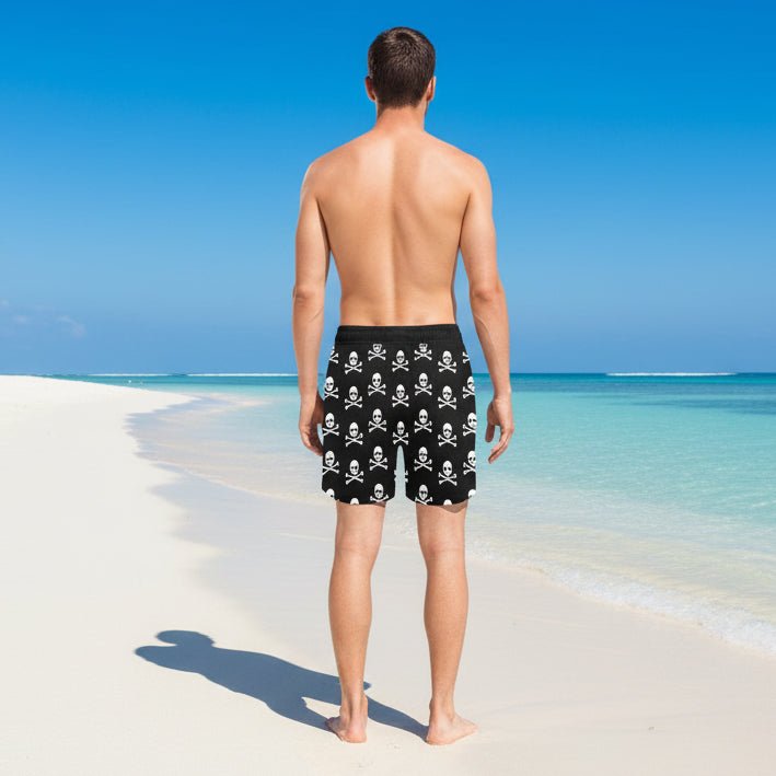 Black shorts with white skull and crossbones pattern worn by a person on a tropical beach