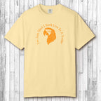 Beige t-shirt with orange graphic and text on a wooden surface