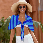 Woman wearing a blue striped swimsuit cover up, white hat, and sunglasses with a blurred background