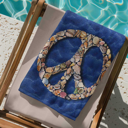 Folded beach towel on a poolside deck chair features a peace sign created entirely out of seashells