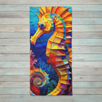A rectangular Beach Towel featuring a colorful geometric seahorse over an ocean scene, displayed against a light gray wood plank background.